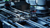 Robotarm tester kretskort på en automatisk produksjonslinje i fabrikkmiljø.