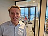 Mann i skjorte står foran glassdør med Kjeller Innovasjon-logo i moderne kontorlandskap.